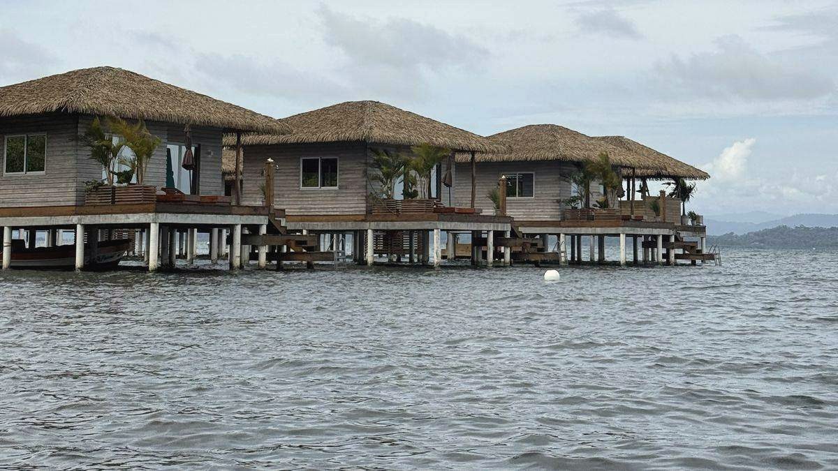 Holzbungalows mit Palmdächern auf Stelzen über dem Meer