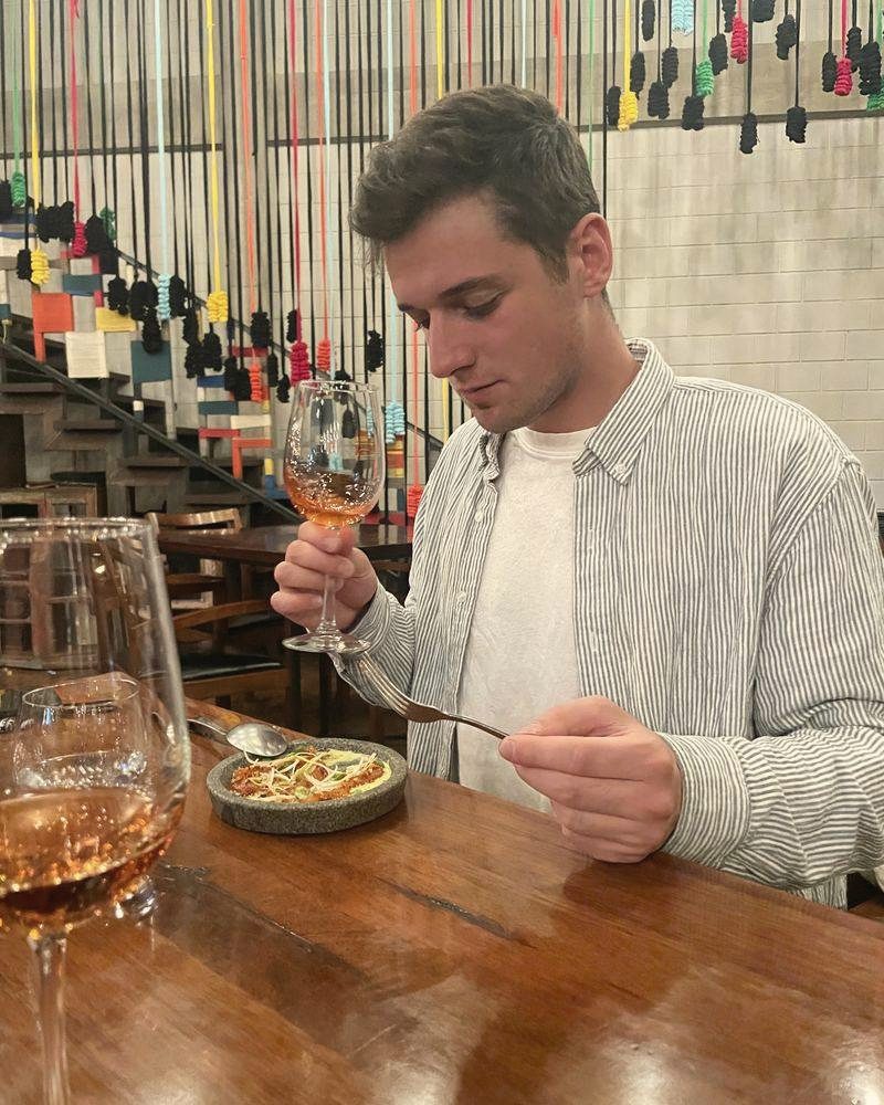 Fabian probiert in einem Restaurant einen Roséwein, vor ihm ein Teller in einer Steinschale
