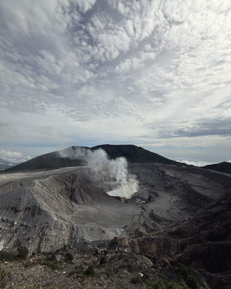 Dampfender Krater eines Vulkans unter Wolken