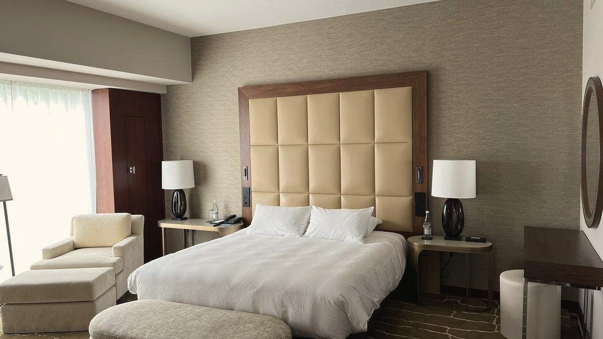 Hotelzimmer mit Doppelbett, Sessel und gepolsterter Bank